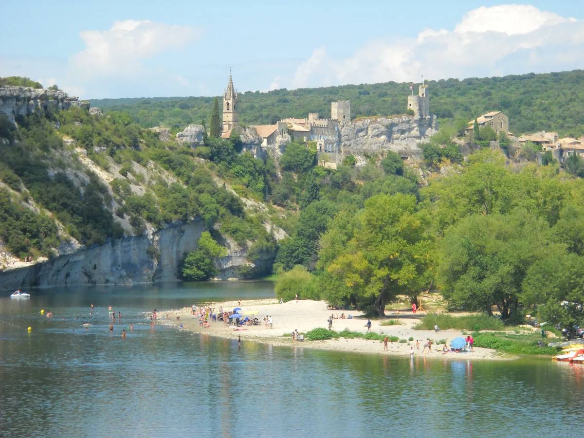 The beach at Saint-Martin in the Ardèche with a view of the village overlooking the river
