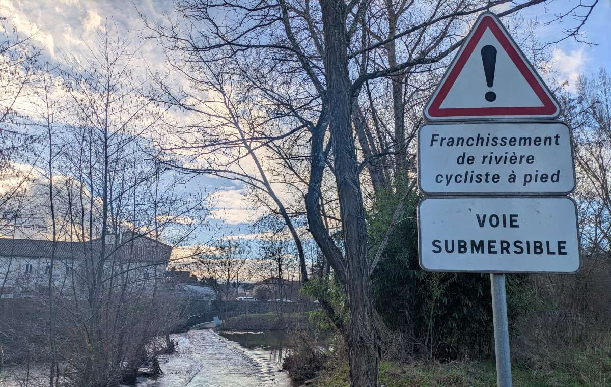 Submersible cycle path crossing the Luol, a tributary of the Ardèche, with a signpost